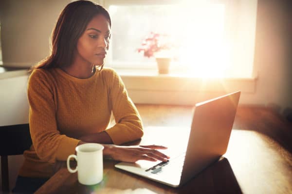 A woman working on her laptop i the morning with a coffee