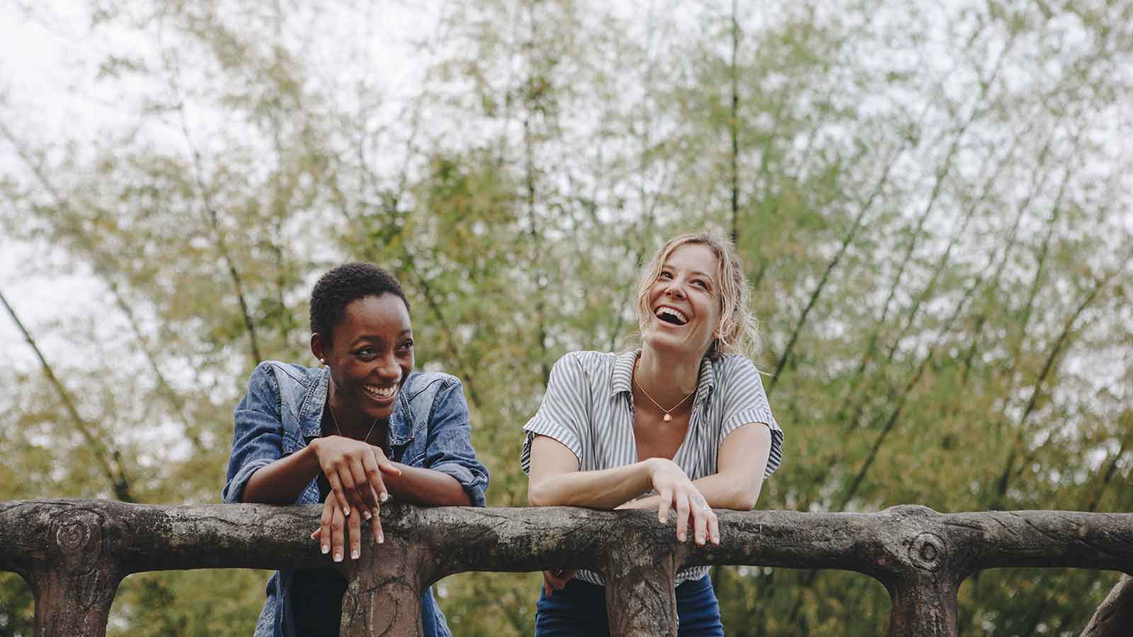 Two women smiling and laughing together outside